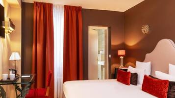 Ein Hotelzimmer mit einem großen Bett, einem Schreibtisch mit Lampe und einem Sessel.