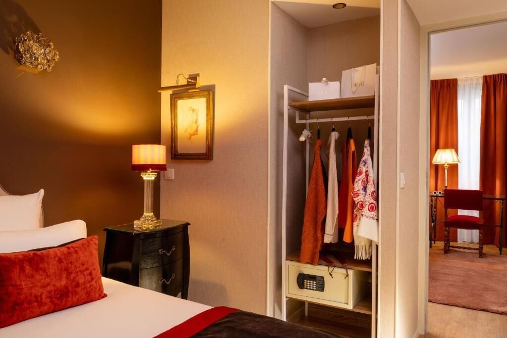 A hotel room with a bed, bedside lamps, a wardrobe, and a chair.