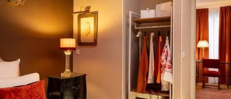 A hotel room with a bed, bedside lamps, a wardrobe, and a chair.