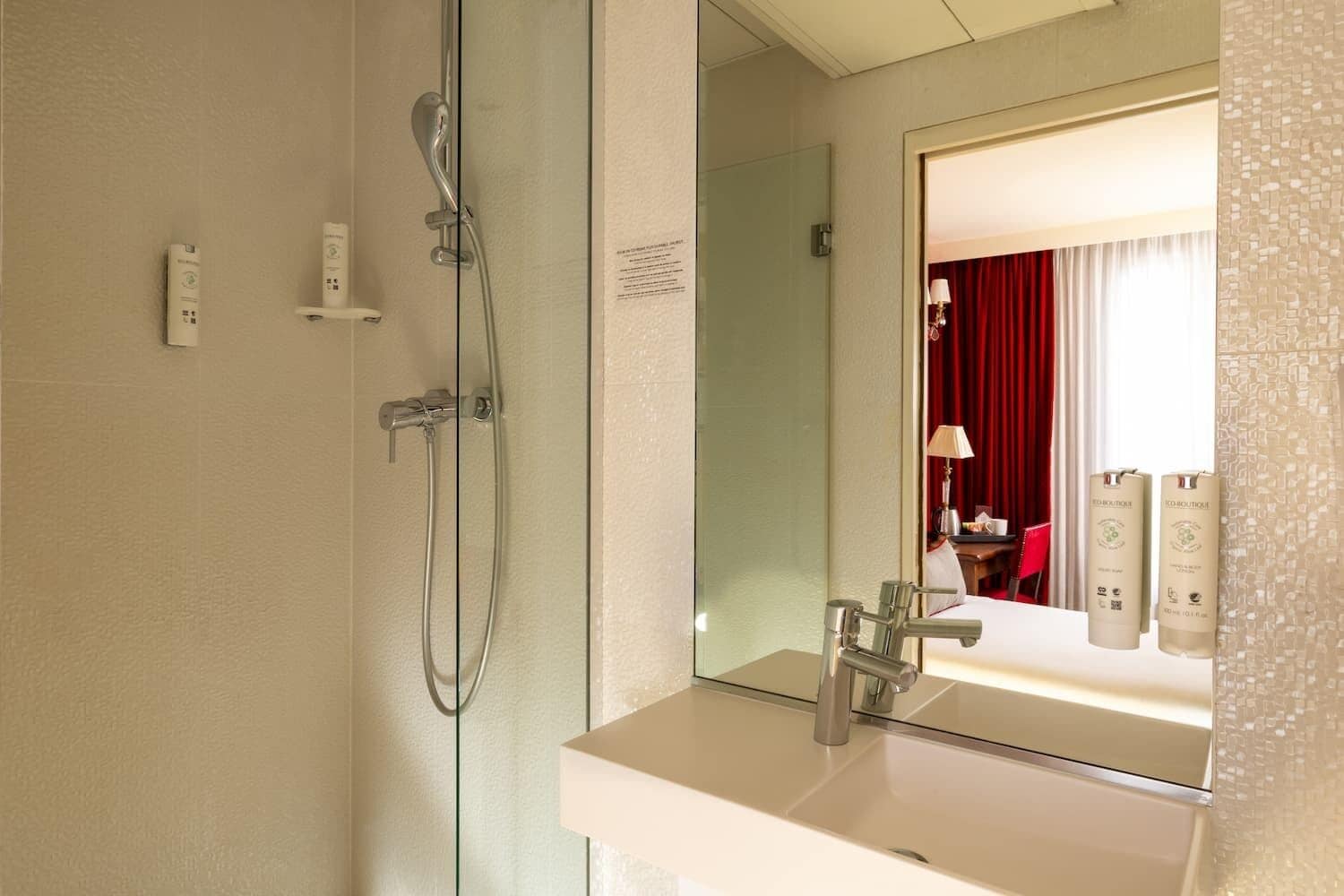 A modern bathroom with a glass-enclosed shower, a large mirror, and a white sink.