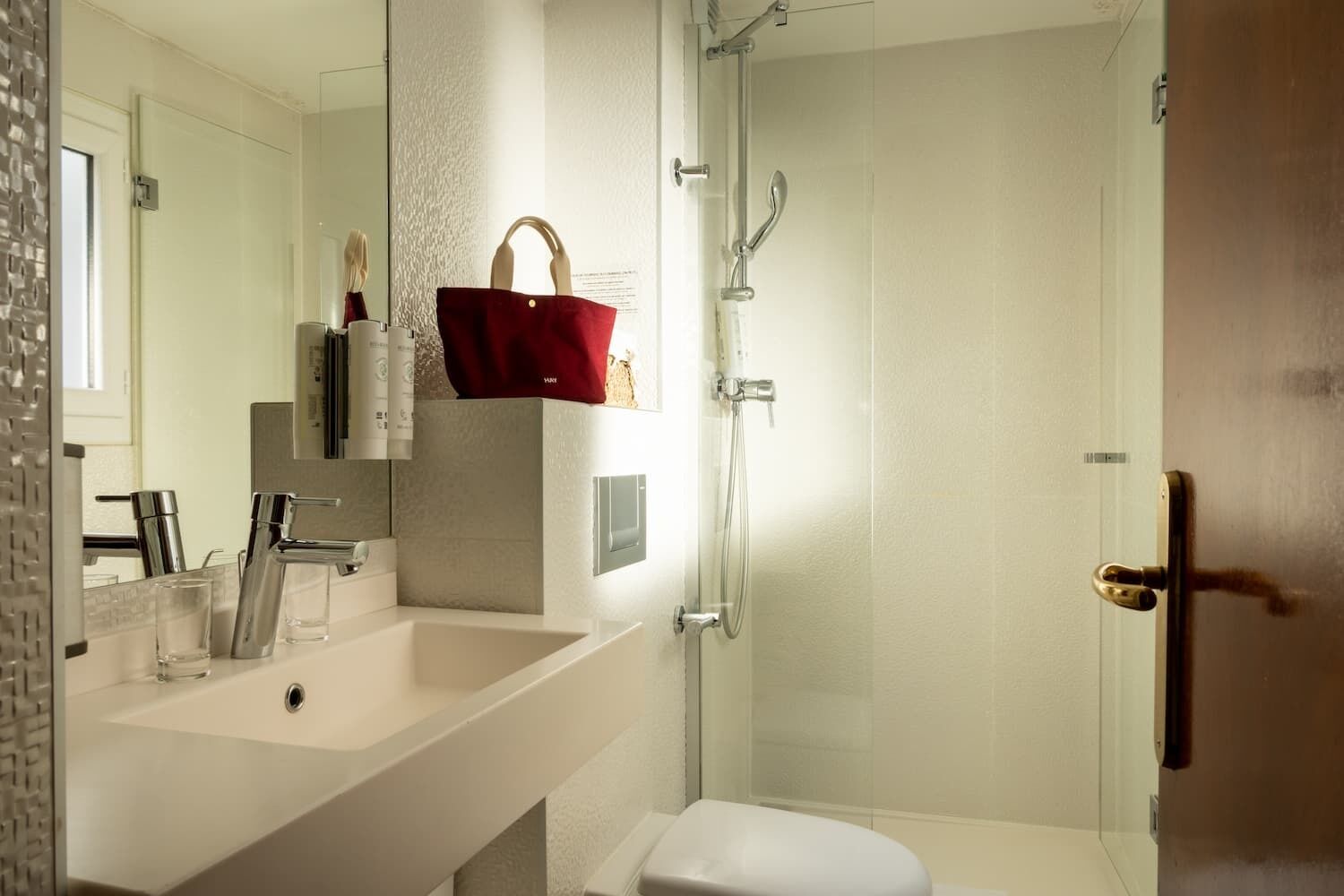 Un baño moderno con un lavamanos grande, espejo y ducha.