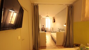 Una habitación de hotel con una cama, una silla, una mesita y un espejo.