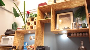 Una cocina con estantes de madera, un microondas, una cafetera y diferentes utensilios de cocina.