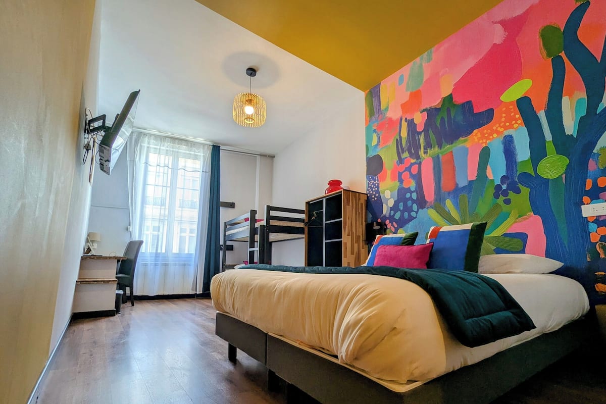 Un dormitorio con cama, escritorio y un cuadro abstracto y colorido en la pared.