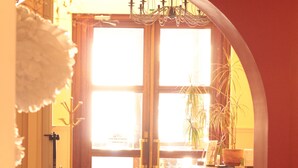 Una habitación con una puerta de madera que da a un espacio luminoso, una silla, una mesa y una planta en maceta.