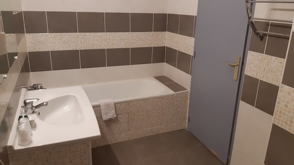 Un baño con bañera, lavamanos y perchero para toallas.