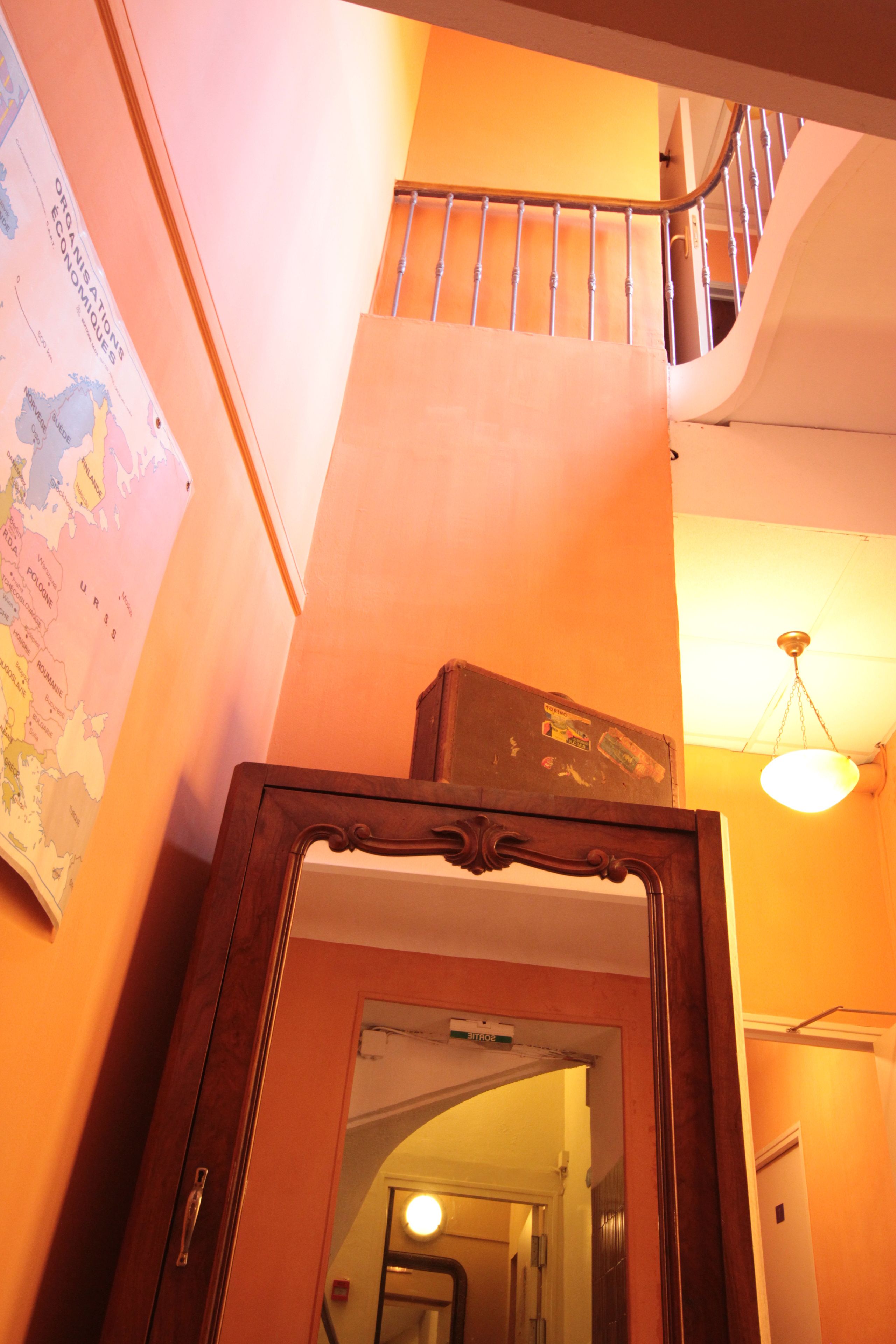 Un escalier avec une rampe en métal, un cadre de porte en bois et une carte accrochée au mur.