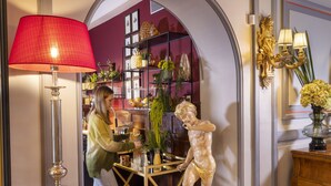 A bar area with a red lamp, a statue, and a shelf with various items. - Hotel de Seine (Paris)