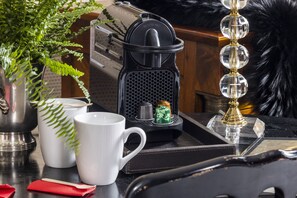 A kitchen counter with a coffee maker, a white mug, a red napkin, a small green plant, and a decorative item. - Hotel de Seine (Paris)