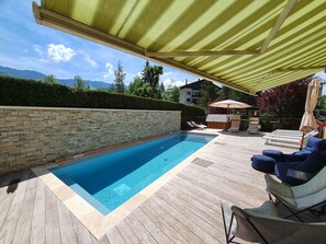 Una piscina al aire libre de temporada, sombrillas, tumbonas