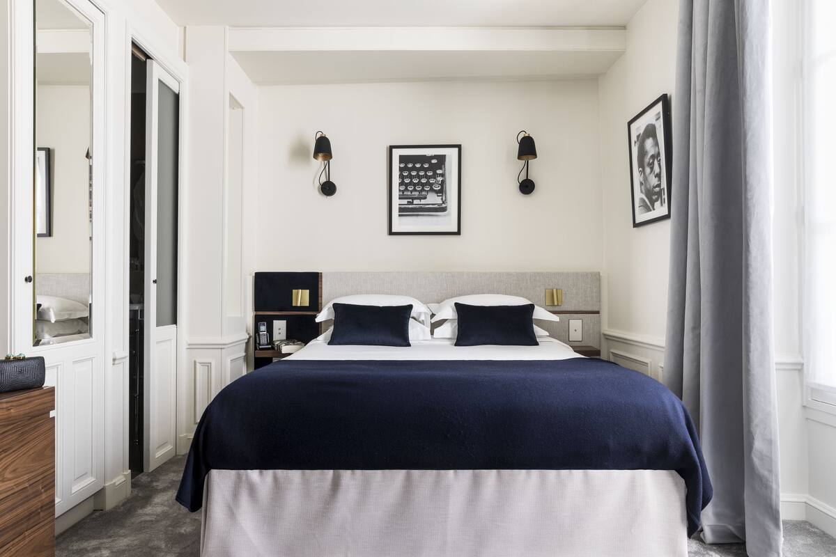 A neatly arranged bedroom with a bed, bedside tables, a wardrobe, and a framed picture on the wall.