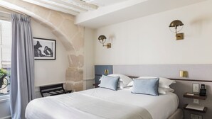 A hotel room with a large bed, two bedside lamps, a nightstand, and a framed picture on the wall. - Hotel Verneuil (Paris)