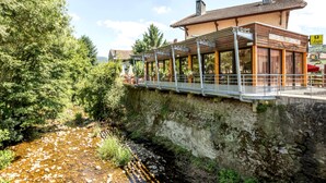 Un restaurante a la orilla del río con terraza al aire libre y vistas a un arroyo.