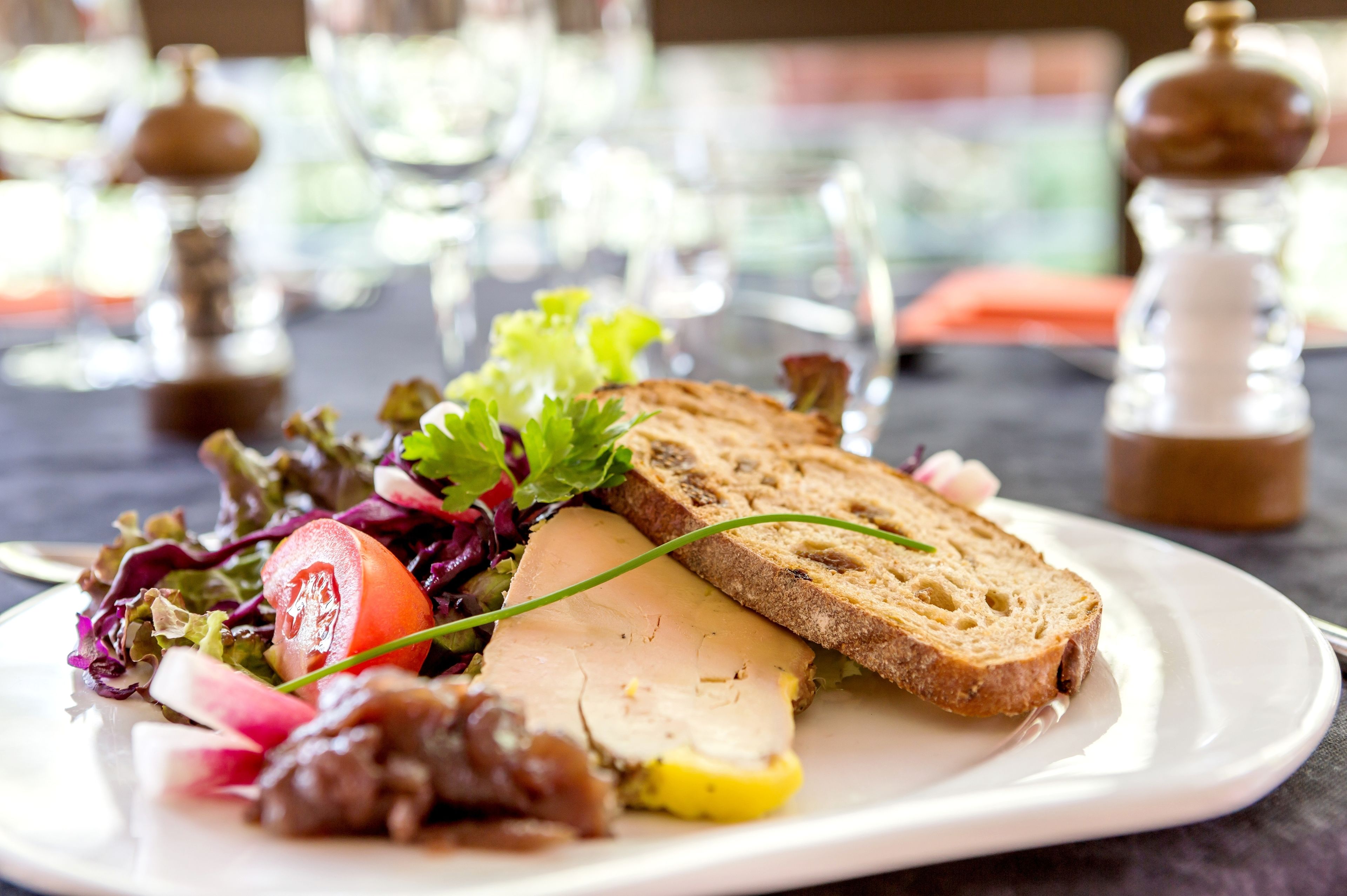 A plate with a salad, sliced turkey, and bread on a table.