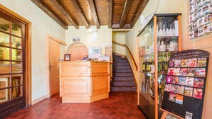 Zona de recepción con mostrador de madera, una escalera y una exposición de postales.