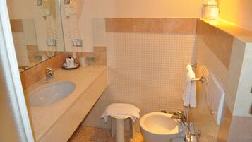 A bathroom with a large bathtub, a sink, and a toilet. There is a towel rack and a mirror above the sink.