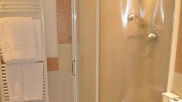 A bathroom with a glass-enclosed shower, a toilet, a sink, and a towel rack.