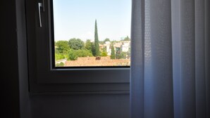 Une fenêtre donnant sur un paysage urbain, avec des bâtiments et des arbres.