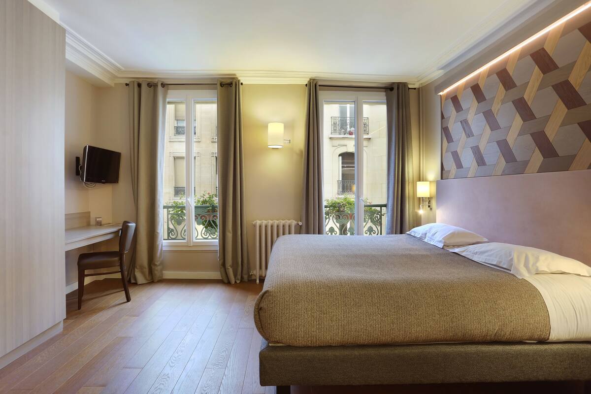 Ein Hotelzimmer mit Bett, Schreibtisch, Stuhl und Fernseher.