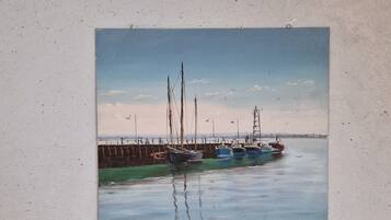 Una pintura de un puerto tranquilo con barcos, un muelle y un cielo despejado.