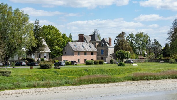 A large, historic building with multiple chimneys, a well-maintained lawn, and a sandy beach area. - Hôtel Rose (Beauvoir)