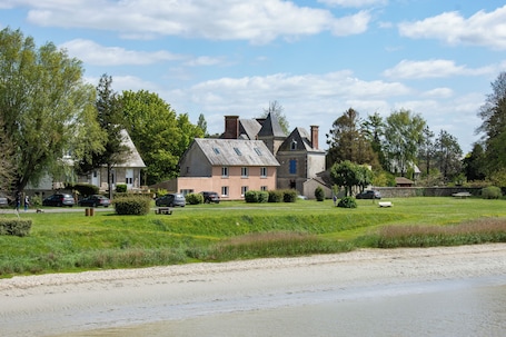 Un grand bâtiment historique doté de nombreuses cheminées, d’une pelouse bien entretenue et d’une zone de plage de sable.. Hôtel Rose