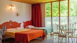 A room with two beds, a table with chairs, a fan, and a window with curtains. - Hôtel Rose (Beauvoir)