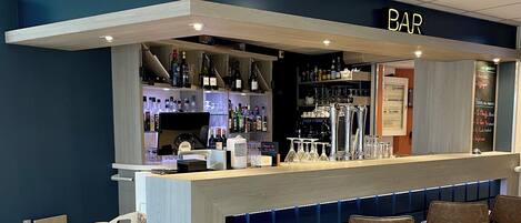 A bar area with a counter, stools, and shelves of bottles.