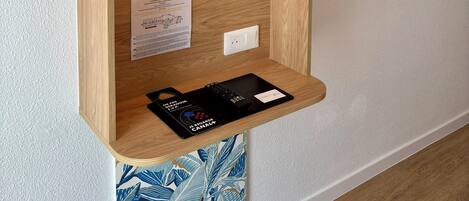 A wall-mounted television, a wooden shelf with a sign, and a wall-mounted light fixture.