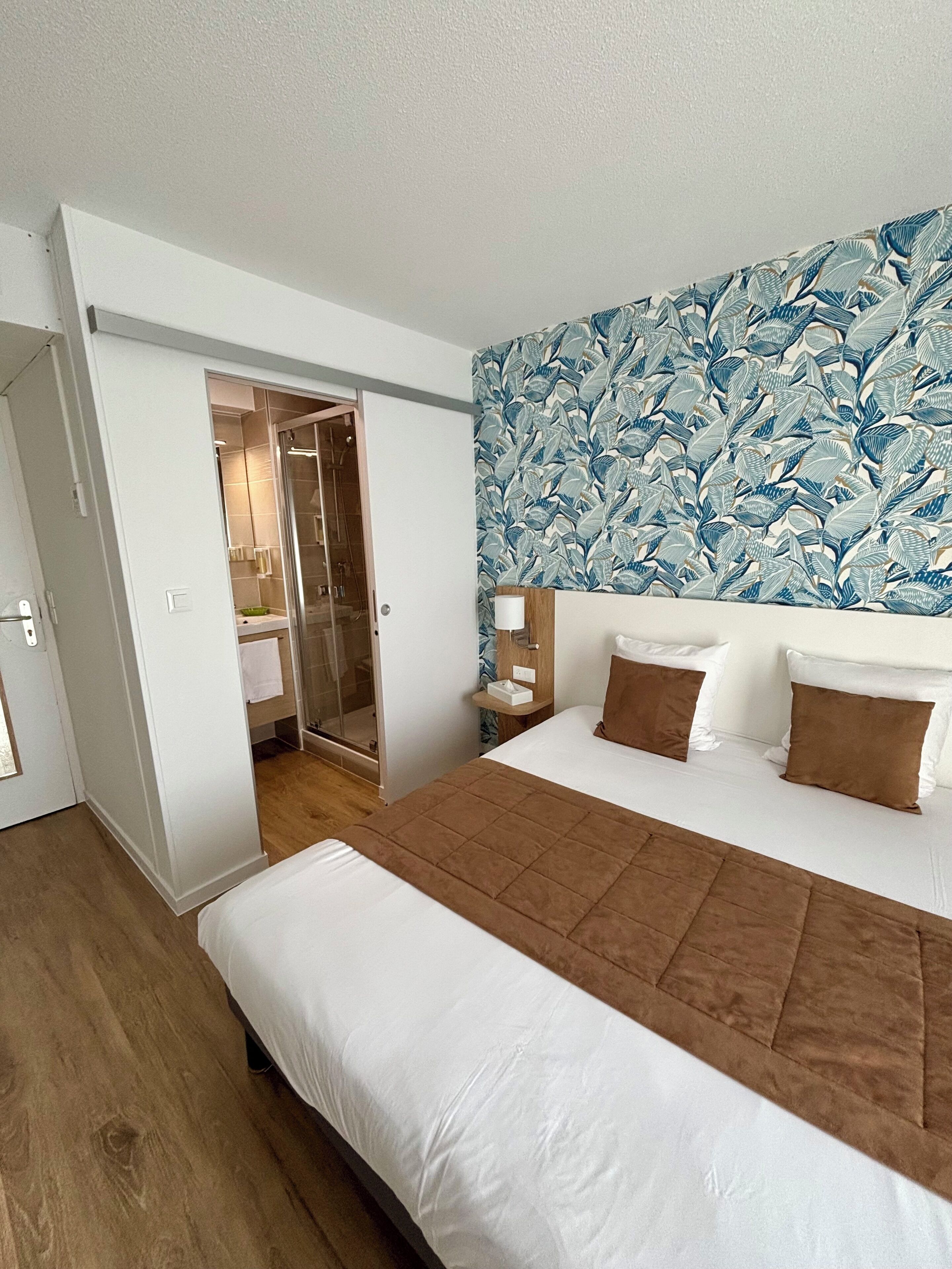 A bedroom with a large bed, a walk-in closet, and a shower.