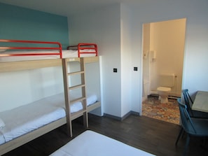 A dormitory room with bunk beds, a small table, and a chair. There is a bathroom with a toilet and a shower. - hotelF1 Reims Tinqueux (Tinqueux)