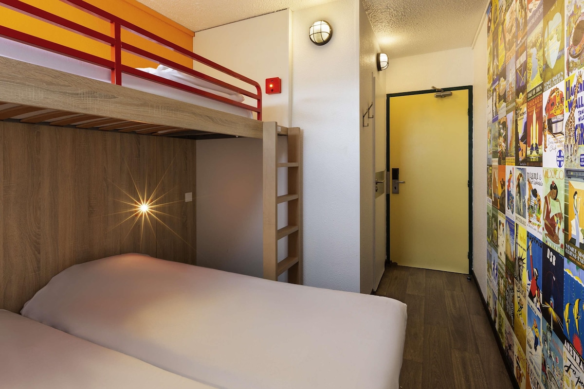 A bunk bed room with a ladder, a wall with posters, and a door.