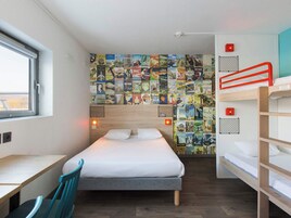A compact hotel room with a single bed, a desk, and a bunk bed.
