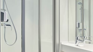 A modern bathroom with a glass shower enclosure, a white sink, and a mirror. - hotelF1 Reims Tinqueux (Tinqueux)