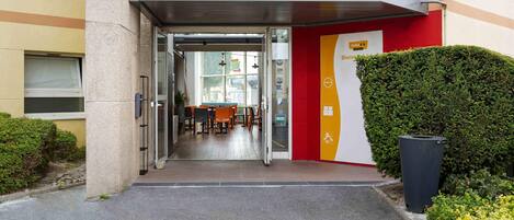 L’entrée d’un hôtel, avec une porte en verre, un comptoir d’accueil et une enseigne.