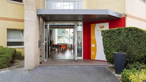 A hotel entrance with a glass door, a reception desk, and a signboard. - hotelF1 Reims Tinqueux (Tinqueux)