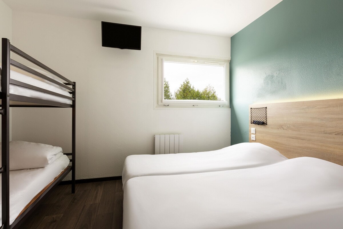 A room with bunk beds, a window, a radiator, and a wall-mounted TV.
