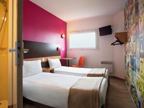 A hotel room with two beds, a window, a TV, and a wall with posters. - hotelF1 Reims Tinqueux (Tinqueux)