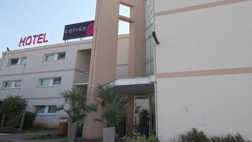 Un hotel con un letrero que dice "HOTEL" y "cerise". Presenta un diseño moderno con varios pisos y balcones.