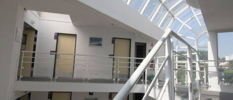 A multi-level interior with a glass ceiling, white railings, and a staircase.