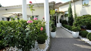 A hotel entrance with a covered walkway, potted plants, and a signboard. - Cottage Hotel (Vandœuvre-lès-Nancy)