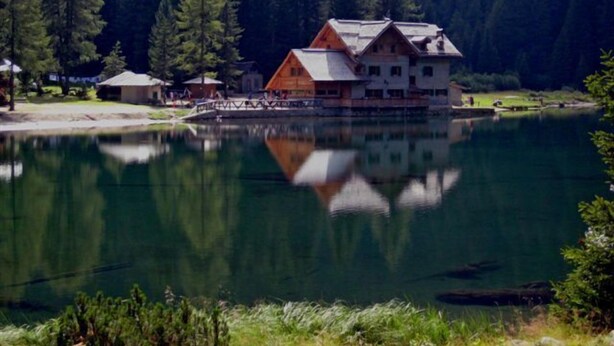A wooden house with a large balcony, surrounded by a forest and a lake. - Dahu (Pinzolo)