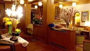 A lobby with wooden paneling, a reception desk, and several chairs. - Dahu (Pinzolo)