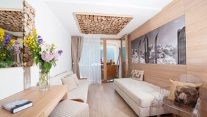 A modern room with a wooden ceiling, a sofa, a chair, a table with a book, and a vase with flowers. - Dahu (Pinzolo)
