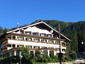 A multi-story hotel with balconies, a mountain backdrop, and a clear sky. - Dahu (Pinzolo)