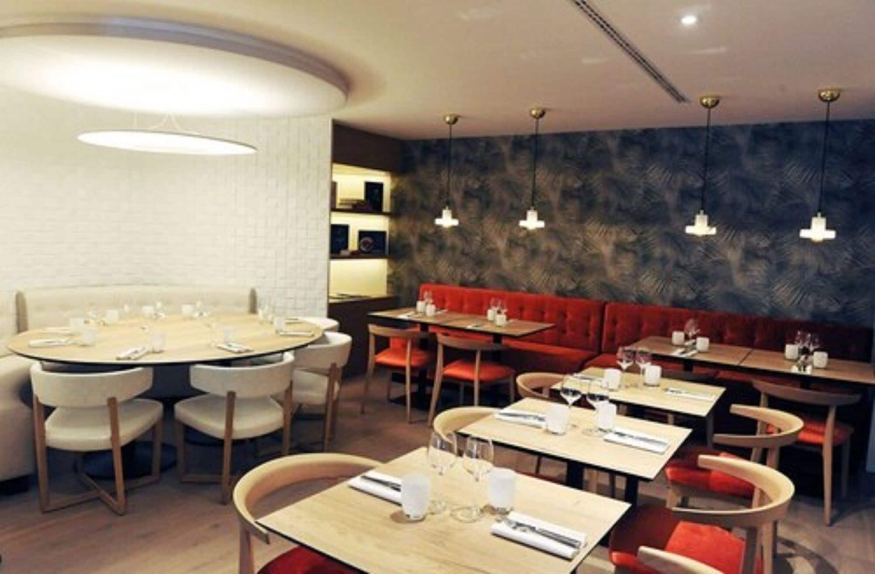 A restaurant with round tables and booths, wooden chairs, and pendant lighting.