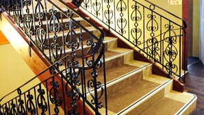 A staircase with ornate black metal railings and wooden steps. - Golfe Hotel (Vannes)