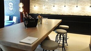 A modern bar area with a wooden counter, bar stools, and a minibar. - Golfe Hotel (Vannes)