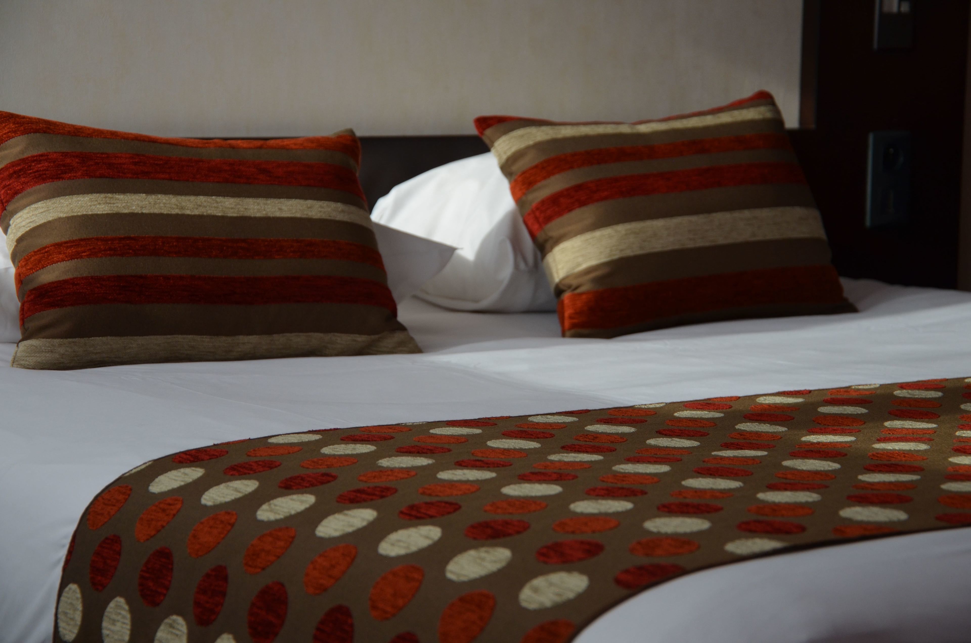 A bed with striped pillows and a patterned throw blanket.