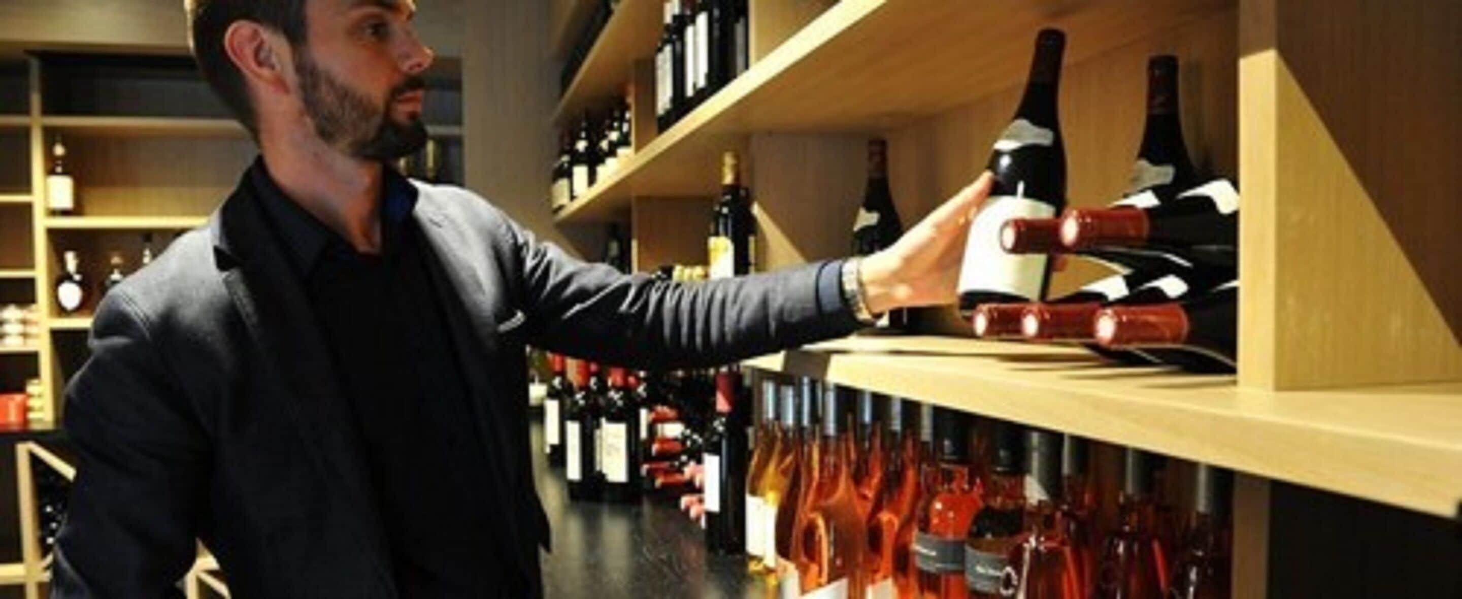A person selecting a wine bottle from a shelf in a wine cellar.